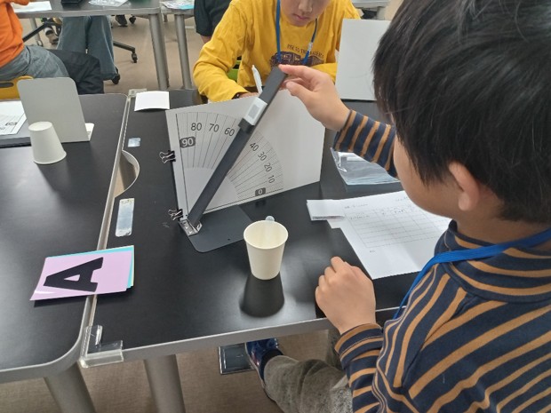 水が転がる角度を測る実験をする子ども
